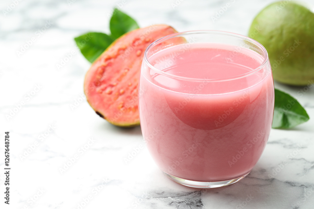 Tasty guava juice in glass, leaves and fruits on white marble table, closeup. Space for text Tasty guava juice in glass, leaves and fruits on white marble table, closeup. Space for text