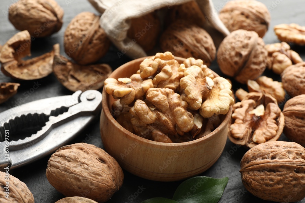 Fresh ripe walnuts, shells and nutcracker on table, closeup Fresh ripe walnuts, shells and nutcracker on table, closeup