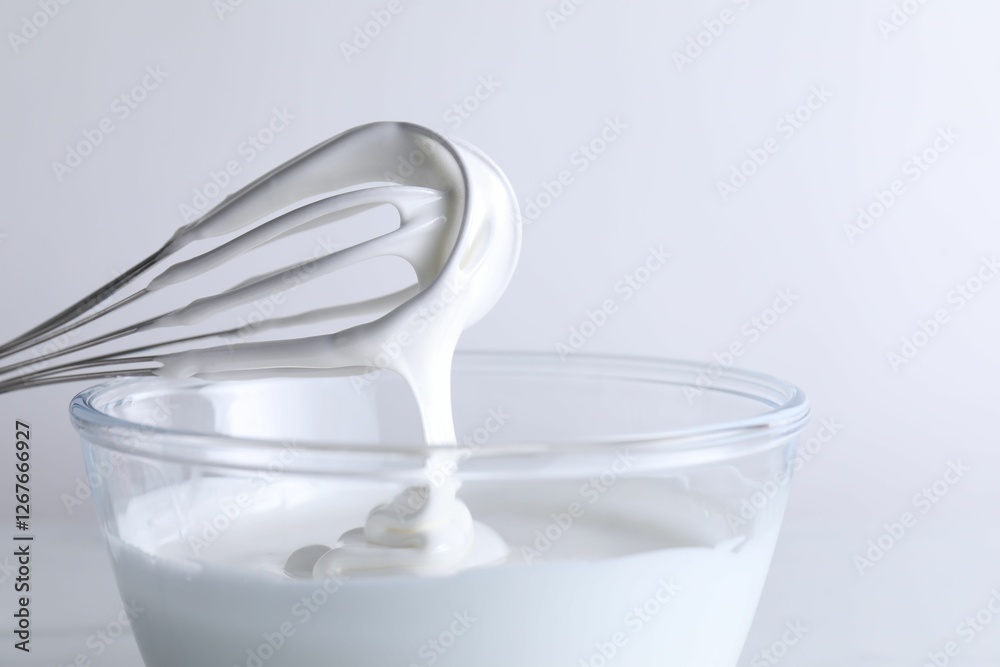 Whisk and bowl with whipped cream on white background, closeup Whisk and bowl with whipped cream on white background, closeup