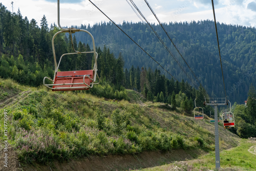 Fototapeta premium Ski lift in green forest. Cableway in Mountains. Summer nature outdoor trees