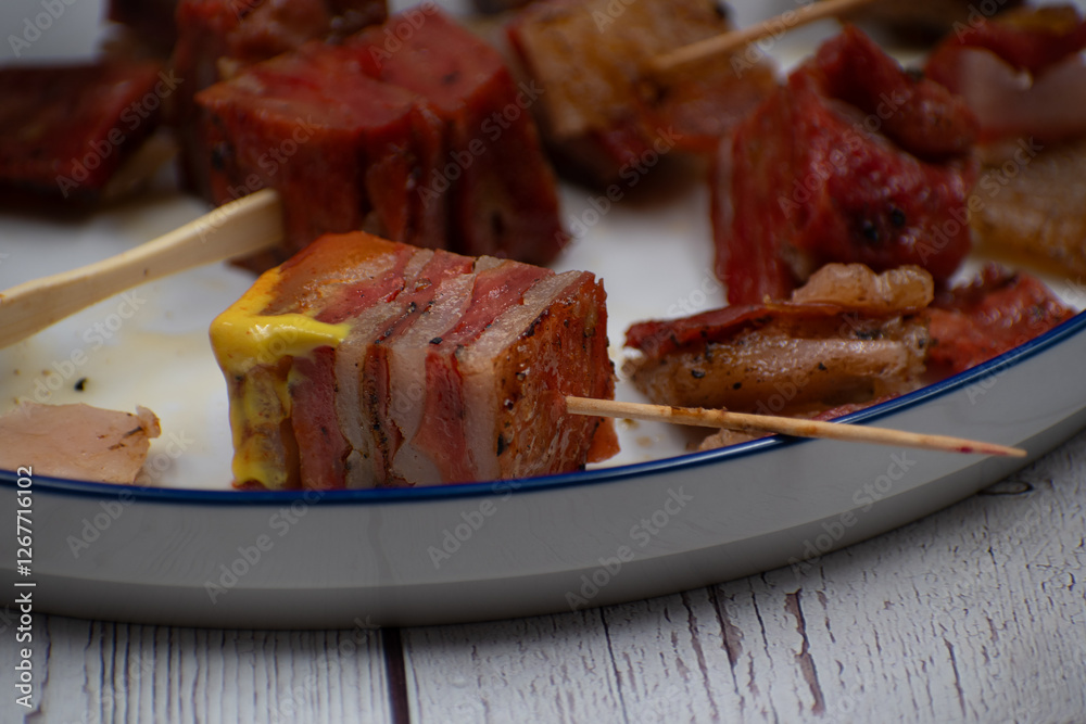 Vegan seitan pork belly appetizer, white plate, wooden table Vegan seitan pork belly appetizer, white plate, wooden table