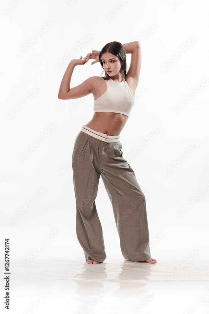 Obraz premium Young girl in trousers posing on a white background
