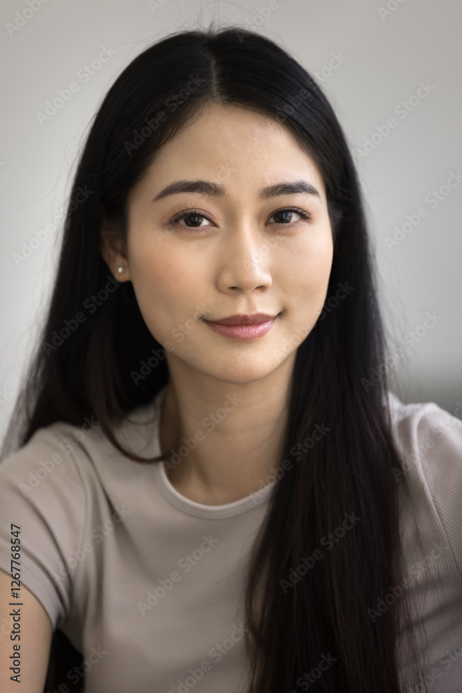 Vertical shot of beautiful Asian woman dressed in casual t-shirt looking at camera with slight smile, exude confidence and calmness while posing alone indoor. Natural beauty, self-care, self-assurance Vertical shot of beautiful Asian woman dressed in casual t-shirt looking at camera with slight smile, exude confidence and calmness while posing alone indoor. Natural beauty, self-care, self-assurance
