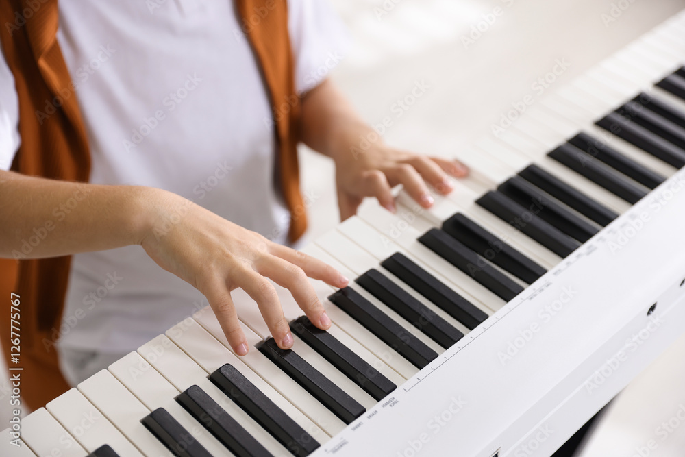 Fototapeta premium Boy playing synthesizer indoors, closeup. Electronic musical instrument