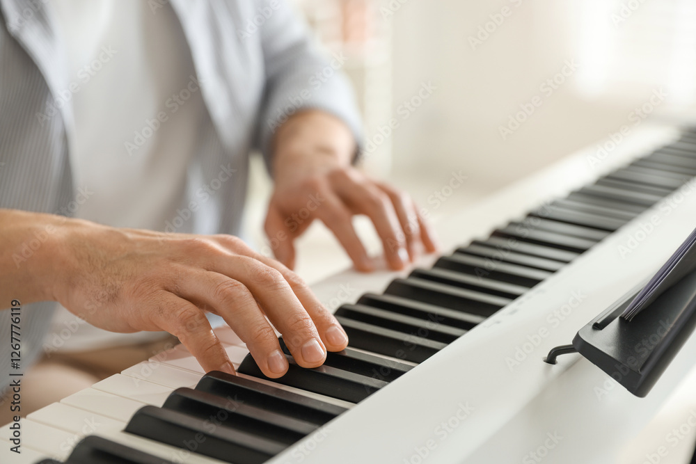 Obraz premium Man playing synthesizer indoors, closeup. Electronic musical instrument
