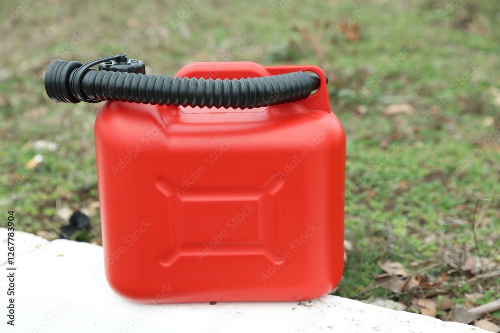One red plastic canister with spout outdoors One red plastic canister with spout outdoors