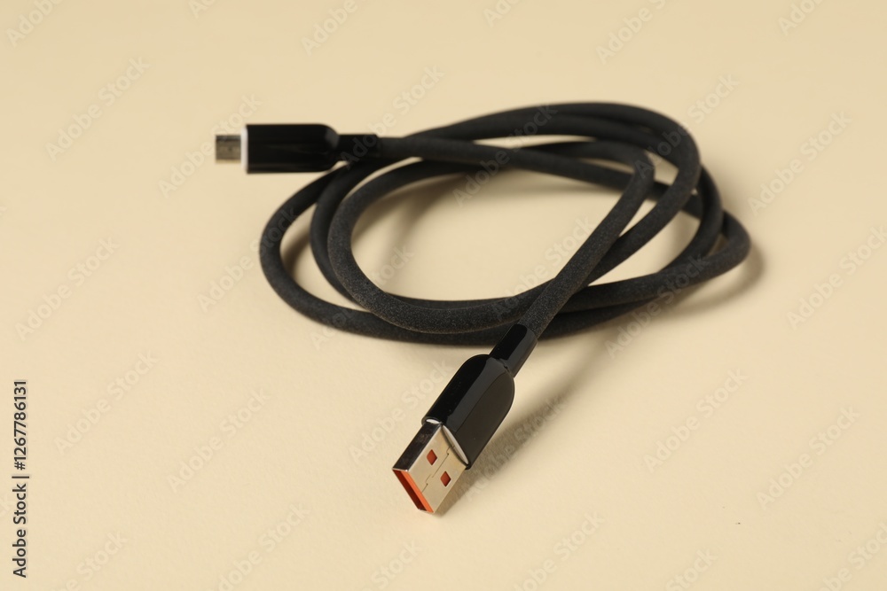 One USB charge cable on beige background, closeup One USB charge cable on beige background, closeup