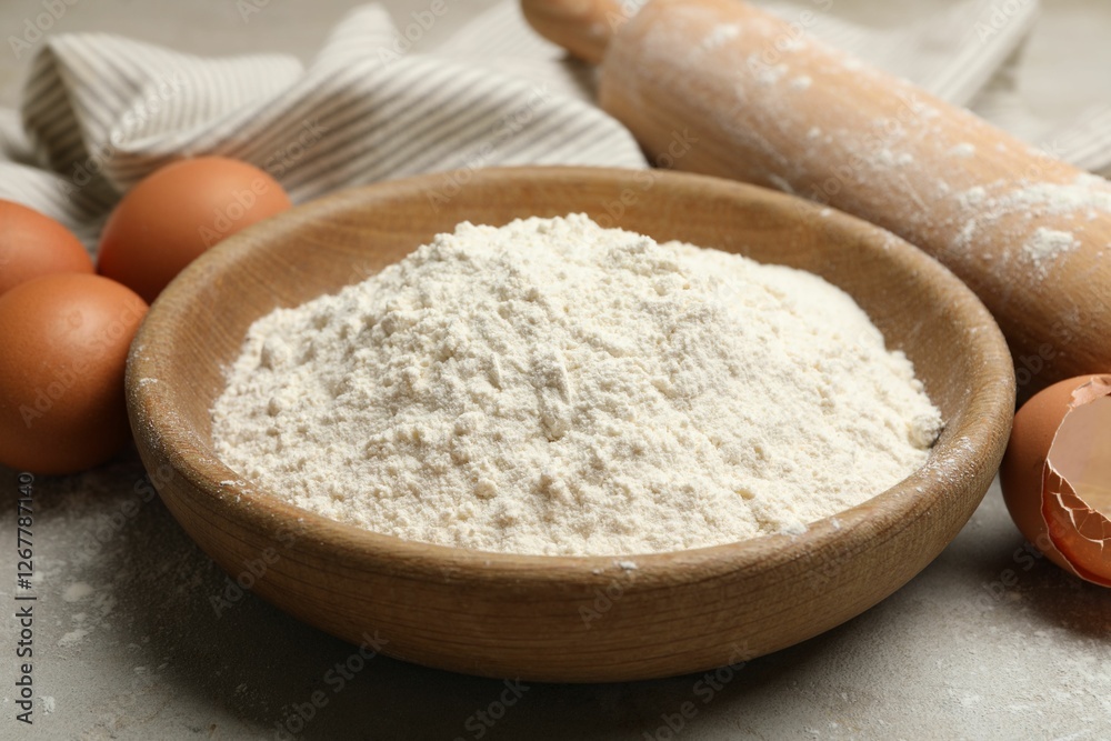 Rolling pin, flour and eggs on light grey background, closeup Rolling pin, flour and eggs on light grey background, closeup