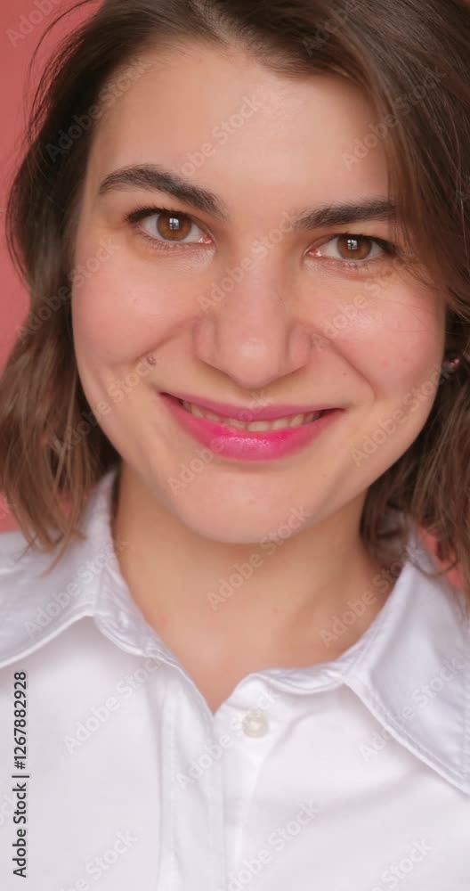 Vertical video of beautiful woman in white shirt smiling on the pink background Vertical video of beautiful woman in white shirt smiling on the pink background