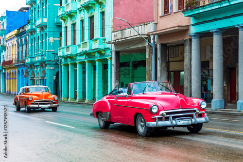red and orange classic cars driving in the streets of havana cuba