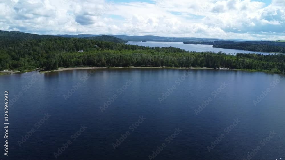 Panoramic aerial view of the large freshwater lake with its sandy beaches constituting its forest shore under a cloudy sky. Lake Matapedia, Quebec,Canada. Panoramic aerial view of the large freshwater lake with its sandy beaches constituting its forest shore under a cloudy sky. Lake Matapedia, Quebec,Canada.