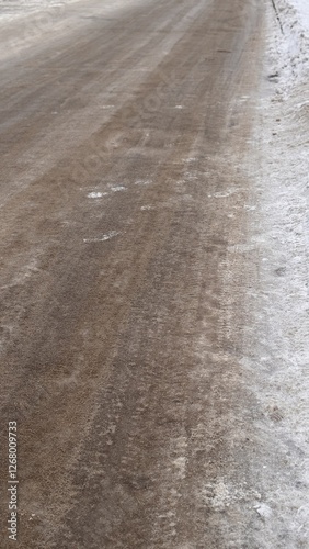 The snowy road has ice, dirt, and other elements impacting driving safety and enjoyment photo