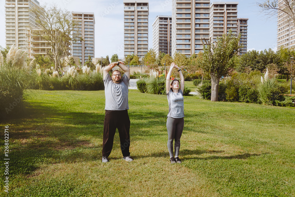 Fototapeta premium Man with extra weight and woman coach doing warm up in the park before jogging