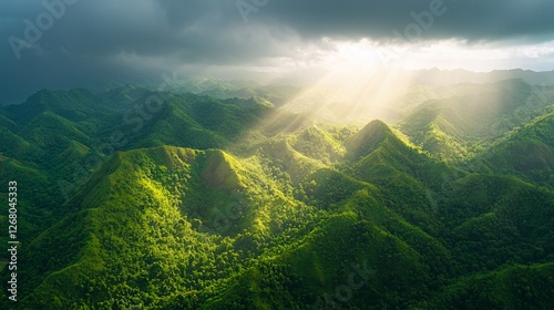 Sun rays through storm clouds over lush green mountains