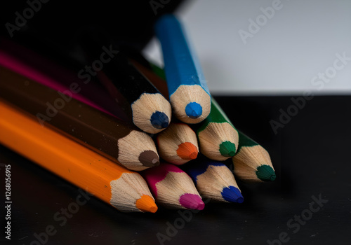 Colorful pencils arranged on a black and white background, showcasing vibrant hues and artistic contrast. The close-up shot highlights the sharp tips and vivid colors. photo