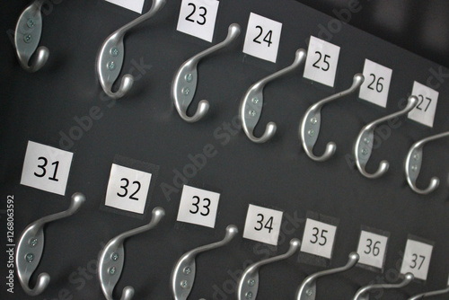Numbered coat hooks on a dark panel in the theater cloakroom. Dressing room equipment
