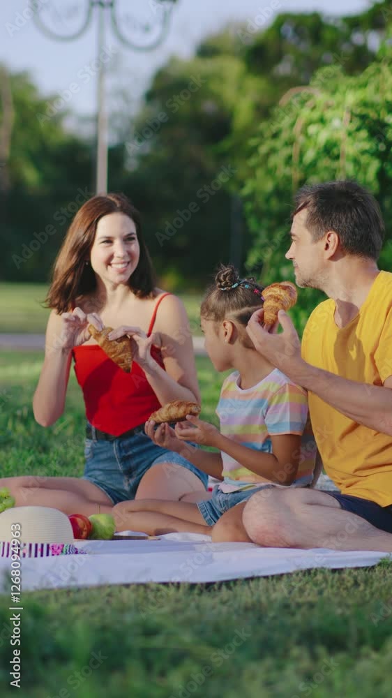 Family enjoys an outdoor picnic in a park on a sunny day while sharing delicious food and laughter Family enjoys an outdoor picnic in a park on a sunny day while sharing delicious food and laughter