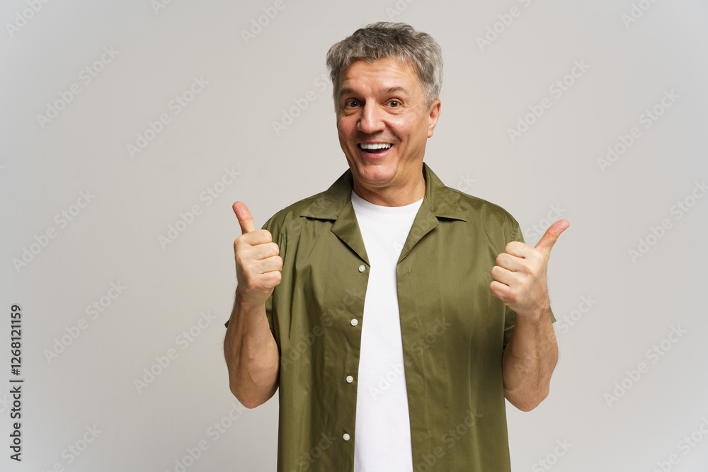 Elderly man smiling and giving thumbs up in a cheerful pose against a light background Elderly man smiling and giving thumbs up in a cheerful pose against a light background