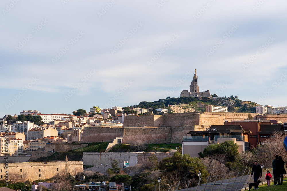 Marseille, France - February 2, 2025: View of Notre-Dame de la Garde, the city's real estate and marina with yachts in the city center. Marseille, France - February 2, 2025: View of Notre-Dame de la Garde, the city's real estate and marina with yachts in the city center.