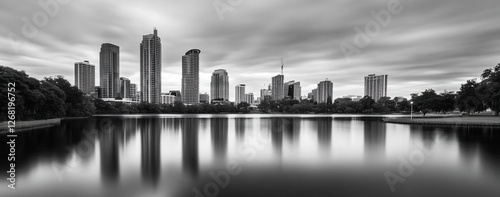 City skyline reflected in calm lake water, black and white.