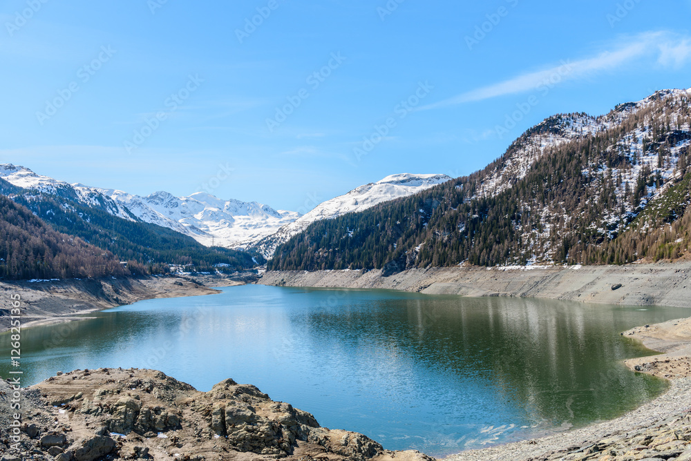 View of a reservoir overlooked by snowy peaks in the Swiss Alps on a clear early spring day View of a reservoir overlooked by snowy peaks in the Swiss Alps on a clear early spring day