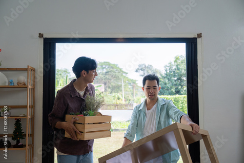 Gay couple carrying boxes and plants while moving into their new house. photo