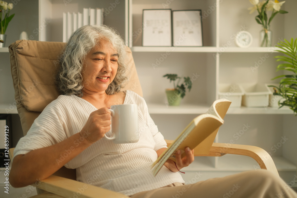 Relaxed senior woman drinking hot tea and reading book on armchair in cozy living room. Relaxed senior woman drinking hot tea and reading book on armchair in cozy living room.