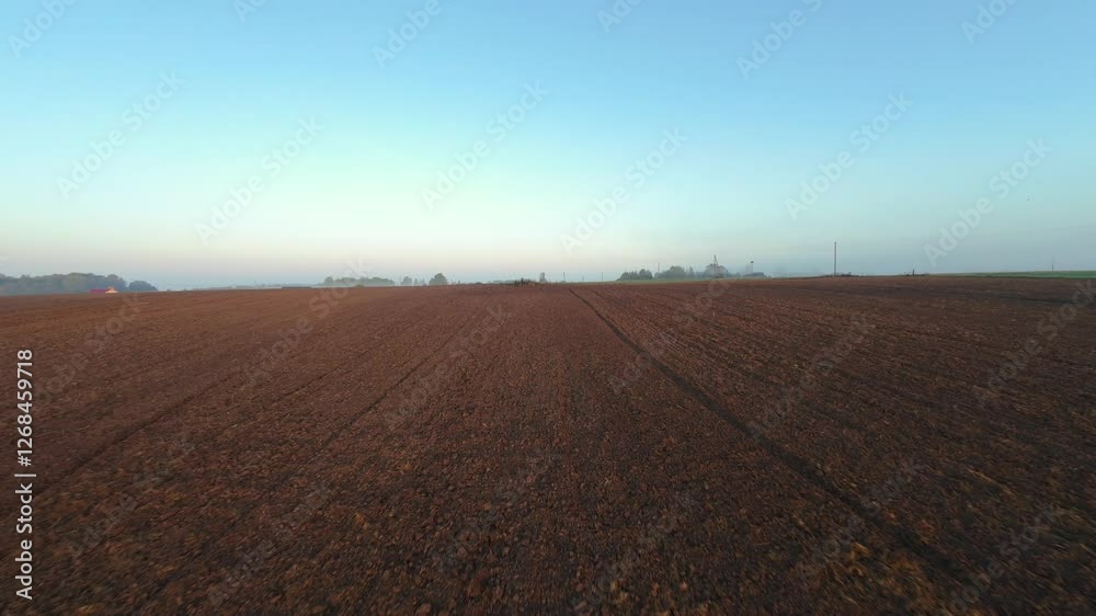 Aerial View of Vast Plowed Field at Sunrise Wide drone shot of freshly plowed field stretching into horizon, with soft morning sky and rural scenery in distance freshly plowed field Aerial View of Vast Plowed Field at Sunrise Wide drone shot of freshly plowed field stretching into horizon, with soft morning sky and rural scenery in distance freshly plowed field