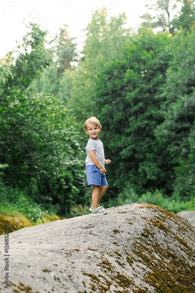 Happy Child Exploring Nature While Standing On Large Rock Happy Child Exploring Nature While Standing On Large Rock