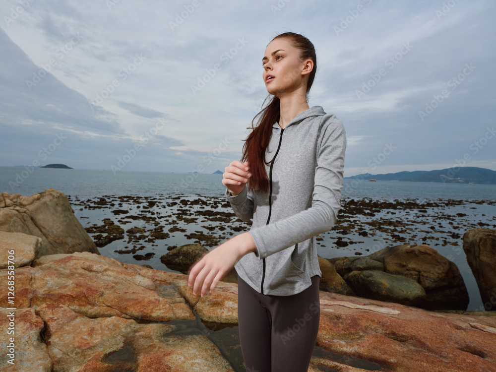 Young woman in athletic wear enjoying nature by the sea, showcasing fitness and relaxation, with a serene beach backdrop and soft clouded sky Young woman in athletic wear enjoying nature by the sea, showcasing fitness and relaxation, with a serene beach backdrop and soft clouded sky