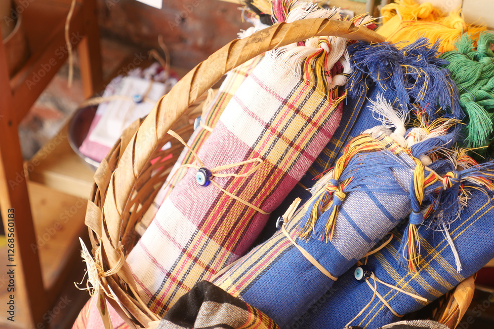 Fototapeta premium Colorful handmade textiles in a woven basket at a market