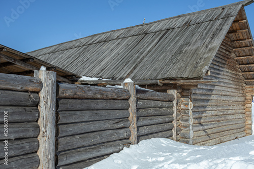 An old wooden barn built in the 19th century. Village barn in Khokhlovka. A barn for keeping livestock in the village in winter. A farm shed for animals. photo