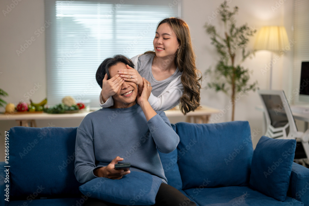 A man and woman are sitting on a blue couch, with the man covering his eyes A man and woman are sitting on a blue couch, with the man covering his eyes