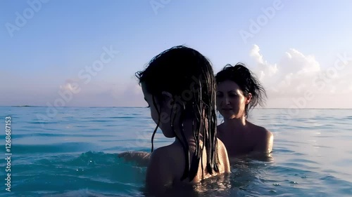 Carefree young girl playing in ocean waves at sunset, silhouetted by warm colors