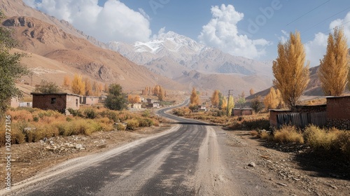 Autumnal mountain road, village, and snow-capped peak