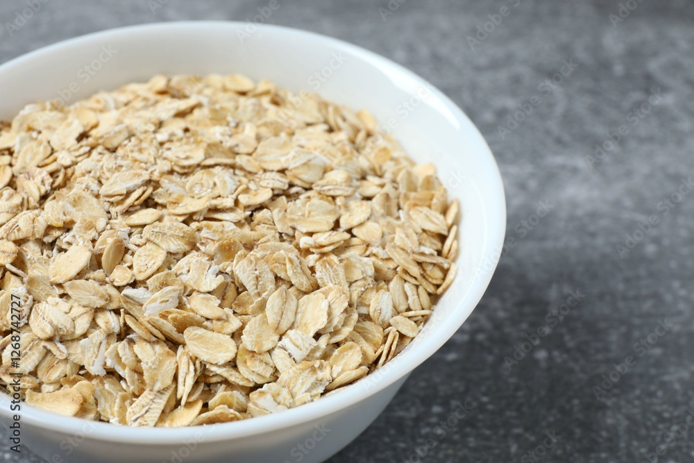 Composition with oatmeal flakes on gray background. Cooking breakfast Composition with oatmeal flakes on gray background. Cooking breakfast