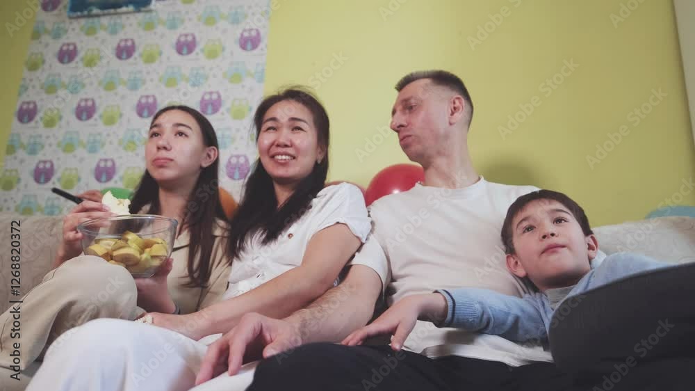 Family sitting on the couch at home and watching TV Family sitting on the couch at home and watching TV