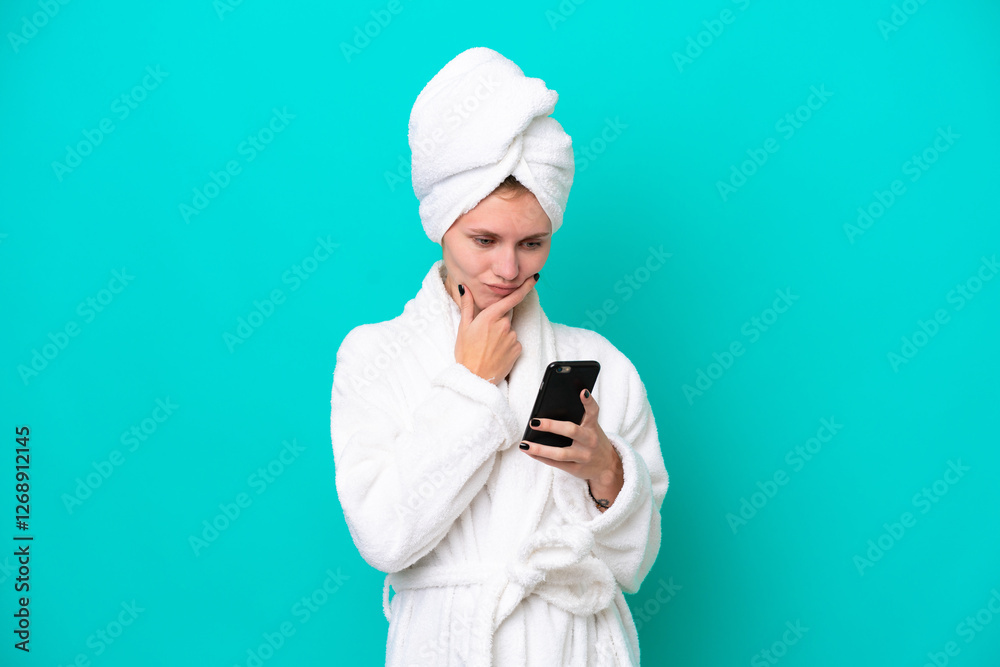 Young woman in a bathrobe isolated on blue background thinking and sending a message Young woman in a bathrobe isolated on blue background thinking and sending a message