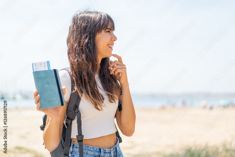 Young woman holding a passport at outdoors thinking an idea and looking side Young woman holding a passport at outdoors thinking an idea and looking side