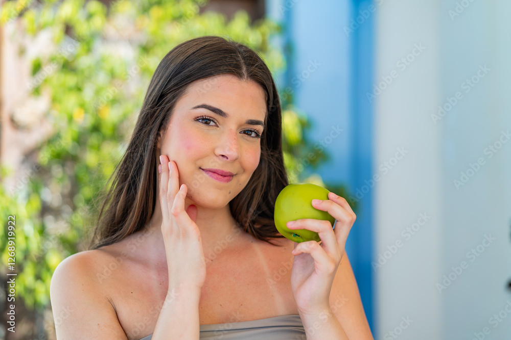 Young pretty Brazilian woman at outdoors holding an apple Young pretty Brazilian woman at outdoors holding an apple