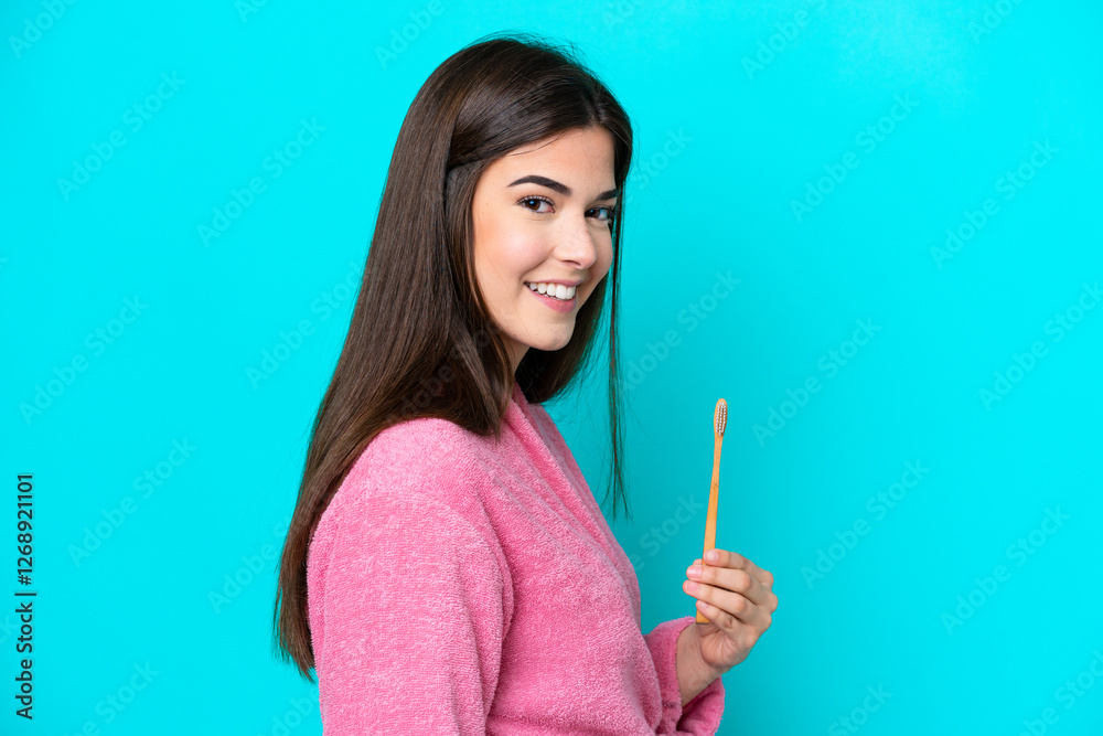 Young Brazilian woman brushing teeth isolated on blue background smiling a lot Young Brazilian woman brushing teeth isolated on blue background smiling a lot