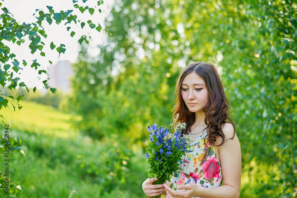 A young woman stands in a lush green forest holding a bouquet of flowers. The scene is serene and peaceful, the girl is surrounded by nature. She is wearing a bright long dress. A young woman stands in a lush green forest holding a bouquet of flowers. The scene is serene and peaceful, the girl is surrounded by nature. She is wearing a bright long dress.