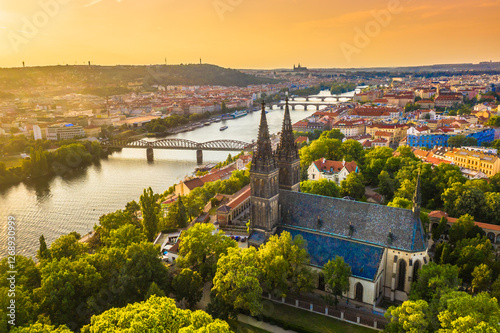 A stunning aerial view of Vyšehrad Castle and the Church of St. Peter and Paul in Prague, Czech Republic, at sunset, showcasing Gothic architecture and the historic fortress above the Vltava River