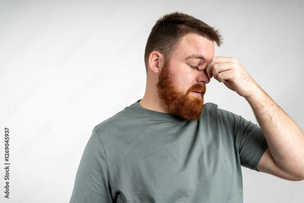 Closeup of young man suffering from headache at home, touching his temples, copy space, isolated background. Migraine, headache, stress, tension problem, hangover concept Closeup of young man suffering from headache at home, touching his temples, copy space, isolated background. Migraine, headache, stress, tension problem, hangover concept