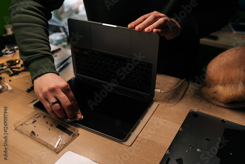Tableau sur toile Top view of unrecognizable technician male carefully wiping screen of laptop with soft cloth, removing dust and fingerprints in professional repair shop environment