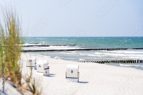 Fototapeta Naklejka Na Ścianę i Meble -  Beach chairs on the beach at the baltic sea with blue ocean in the background and dune grass in the foreground