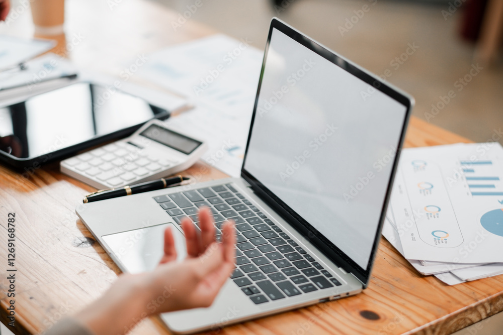 Open laptop on a wooden table surrounded by business documents and a tablet, ideal for corporate and technology themes. Open laptop on a wooden table surrounded by business documents and a tablet, ideal for corporate and technology themes.