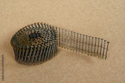 A coil of nail gun framing nail isolated on brown