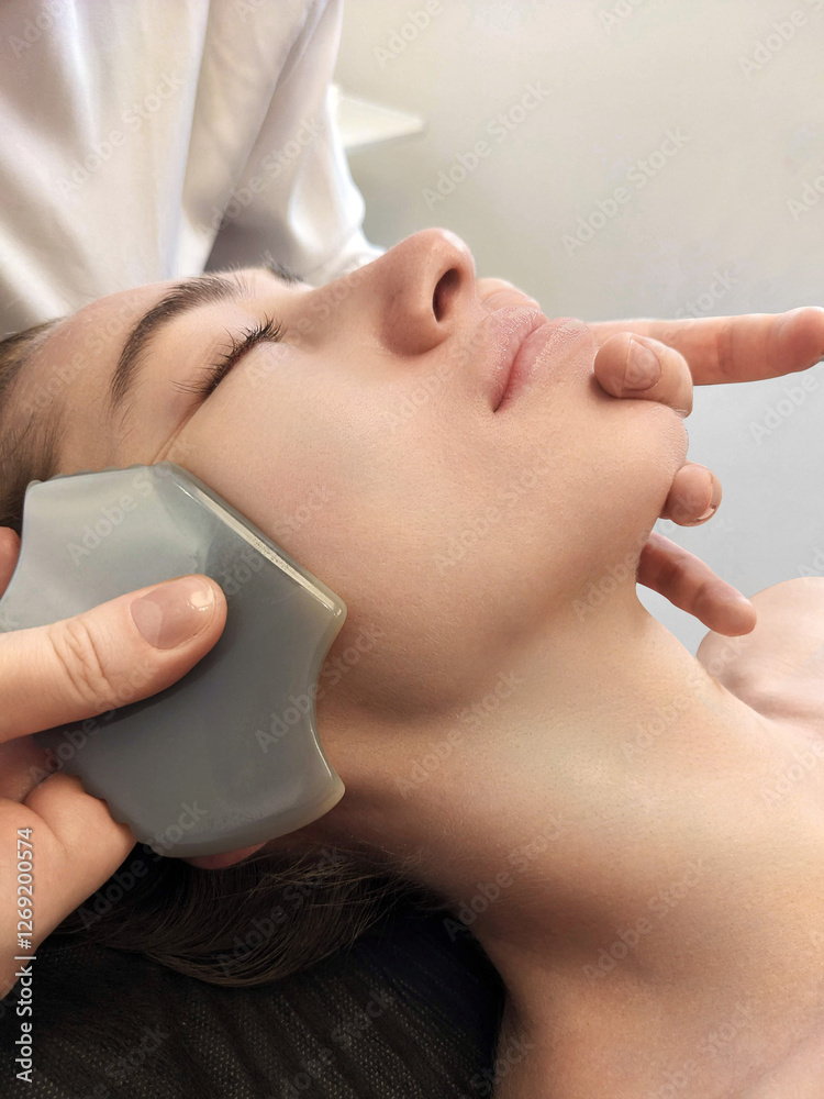 Fototapeta premium Spa facial massage. A young European girl gets a face, neck and head massage. Cosmetic care, face washing.