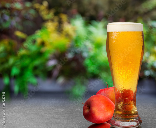 A glass of cider lemonade is next to a couple of apples